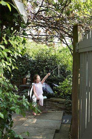 Young girl (5-6) sitting in garden in fairy costume holding magic wand Stock Photo - Premium Royalty-Free, Code: 693-03307189