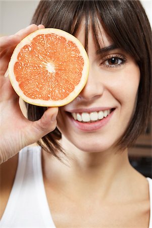 fruit eyes not children - Woman holding half of grapefruit in front of face, portrait, close up Stock Photo - Premium Royalty-Free, Code: 693-03307257