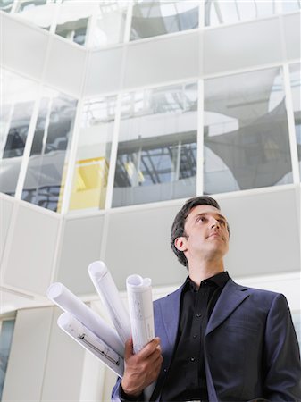 simsearch:693-03311520,k - Homme d'affaires tenant roulé bleus sous le bras dans l'atrium de l'édifice à bureaux, vue d'angle faible Photographie de stock - Premium Libres de Droits, Code: 693-03307382