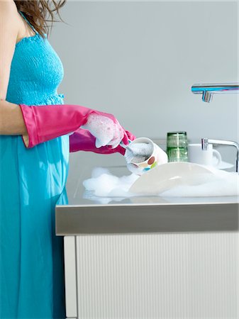 Woman wearing dress and rubber gloves, washing dishes, side view, mid section Stock Photo - Premium Royalty-Free, Code: 693-03307441