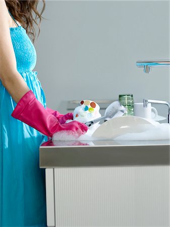 simsearch:614-02243919,k - Woman wearing dress and rubber gloves, washing dishes, side view, mid section Foto de stock - Sin royalties Premium, Código: 693-03307442