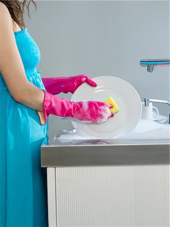 Woman wearing dress and rubber gloves, washing dishes, side view, mid section Stock Photo - Premium Royalty-Free, Code: 693-03307443