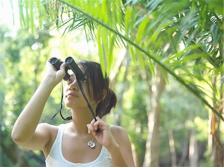 simsearch:693-03307574,k - Young woman in tropical forest looking through binoculars Stock Photo - Premium Royalty-Free, Code: 693-03307512