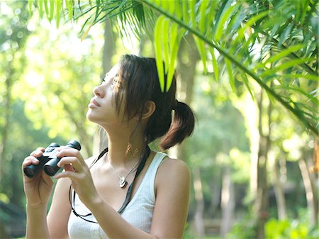 simsearch:693-03307574,k - Young woman in tropical forest, holding binoculars Stock Photo - Premium Royalty-Free, Code: 693-03307513
