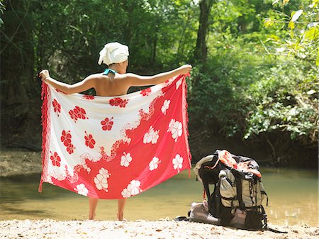 Young woman standing by lake, wrapping with sarong, back view Stock Photo - Premium Royalty-Free, Code: 693-03307522