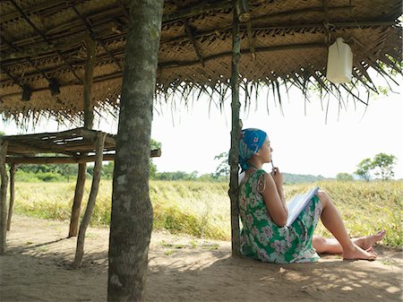 rooftop hut - Young woman wearing dress sitting in shade of hut Stock Photo - Premium Royalty-Free, Code: 693-03307532