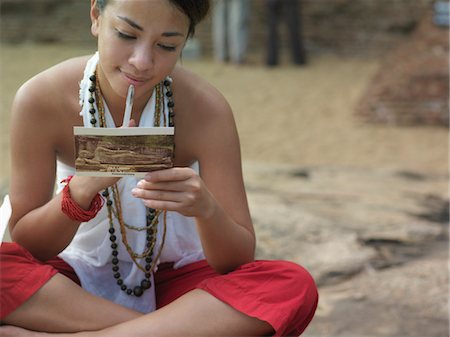 Jeune femme assise sur le rocher, lecture de carte postale, moyenne section Photographie de stock - Premium Libres de Droits, Code: 693-03307559