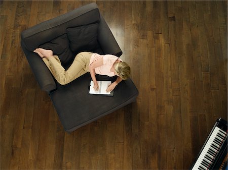 Mid-adult woman lying on sofa, writing in notebook, view from above Foto de stock - Sin royalties Premium, Código: 693-03307595