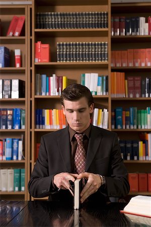 person opening shirt - Man wearing suit opening book at desk in library Stock Photo - Premium Royalty-Free, Code: 693-03307793