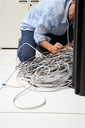 Man working on tangle of computer wires in office Stock Photo - Premium Royalty-Free, Code: 693-03307868