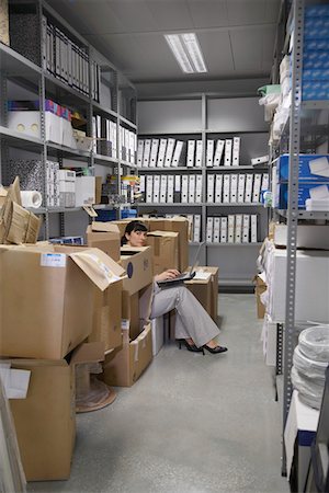 storeroom - Woman using laptop, between boxes in storage room Stock Photo - Premium Royalty-Free, Code: 693-03307953