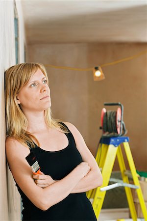 simsearch:693-03308062,k - Pensive woman leaning against wall, ladder in background Fotografie stock - Premium Royalty-Free, Codice: 693-03308070
