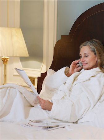 simsearch:693-03307594,k - Woman wearing bathrobe using mobile phone, lying on bed Stock Photo - Premium Royalty-Free, Code: 693-03308110