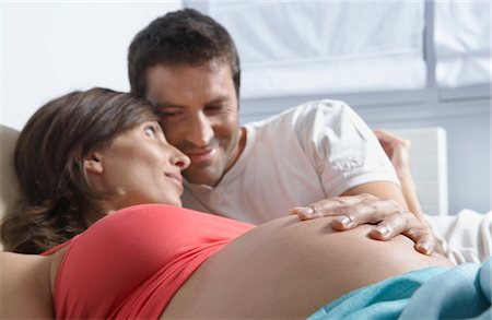 pregnant couple couch - Homme de toucher le ventre de femme enceinte se coucher dans la chambre Photographie de stock - Premium Libres de Droits, Code: 693-03308181