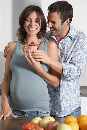 family prepare cake - Man handing pregnant woman strawberry shortcake in kitchen Stock Photo - Premium Royalty-Free, Code: 693-03308202