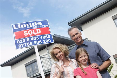 sold - Parents and daughter (7-9) embracing outside new home, portrait Stock Photo - Premium Royalty-Free, Code: 693-03308236