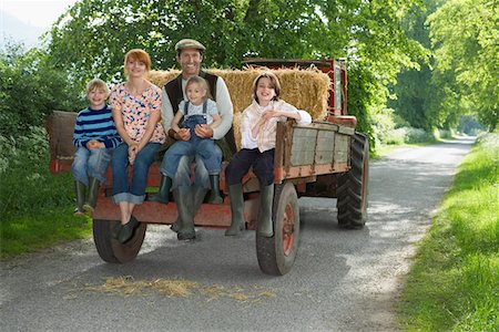 simsearch:693-03308429,k - Parents with three children (5-9) sitting on trailer on country lane, portrait Stock Photo - Premium Royalty-Free, Code: 693-03308329