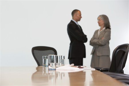 Business couple standing by conference table, focus on table Stock Photo - Premium Royalty-Free, Code: 693-03308797