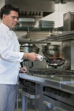 Chef cooking food using frying pan in kitchen Foto de stock - Sin royalties Premium, Código: 693-03308910