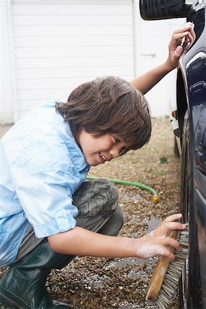 Boy (7-9) washing car wheel with brush Stock Photo - Premium Royalty-Free, Code: 693-03309203