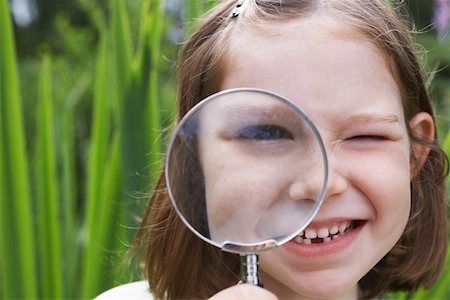 Portrait of girl (7-9) looking through magnifying glass Stock Photo - Premium Royalty-Free, Code: 693-03309212