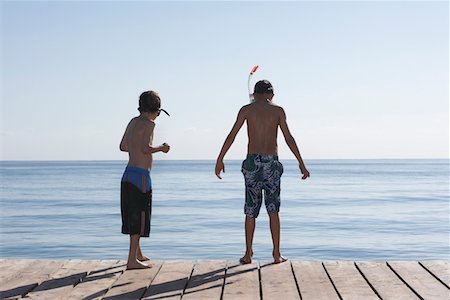 simsearch:693-03314791,k - Two boys (7-11) on jetty wearing snorkelling masks, back view Stock Photo - Premium Royalty-Free, Code: 693-03309308