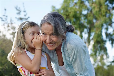 Young blonde girl whispering in grandmother's ear Stock Photo - Premium Royalty-Free, Code: 693-03309302