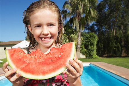 Portrait of girl (5-6) eating watermelon by swimming pool Stock Photo - Premium Royalty-Free, Code: 693-03309343