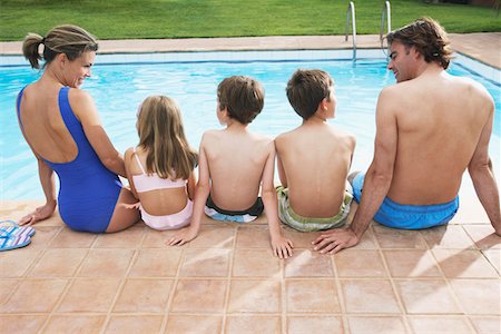 preteen girl swimsuit rear view - Family with three children (6-11) sitting by pool, back view Stock Photo - Premium Royalty-Free, Code: 693-03309365