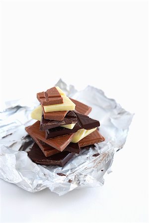 Stack of different chocolate pieces on aluminum foil,  studio shot Stock Photo - Premium Royalty-Free, Code: 693-03309558