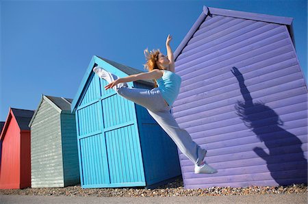 Woman jumping in front of beach huts Foto de stock - Sin royalties Premium, Código: 693-03309859