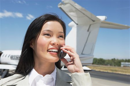 simsearch:693-03303406,k - Smiling Businesswoman standing outside Airplane, talking on mobile Foto de stock - Sin royalties Premium, Código: 693-03300020