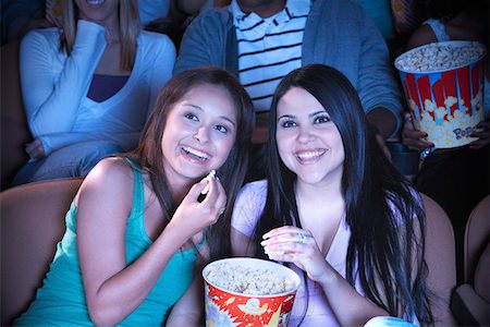 Two young women sharing popcorn in cinema Stock Photo - Premium Royalty-Free, Code: 693-03300034