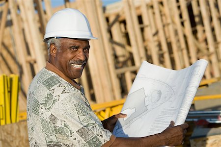 Middle-aged man in hard hat holding blueprint in front of house construction site Stock Photo - Premium Royalty-Free, Code: 693-03300059