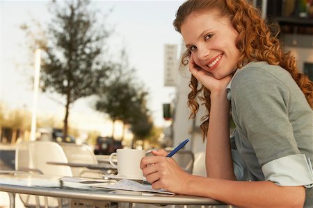 Young woman writing at outdoor cafe, portrait Stock Photo - Premium Royalty-Free, Code: 693-03300231