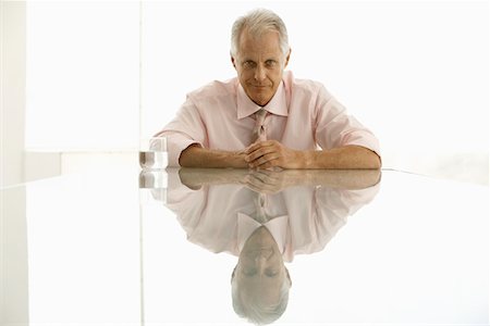 simsearch:693-03564532,k - Businessman sitting at table, portrait Stock Photo - Premium Royalty-Free, Code: 693-03300301