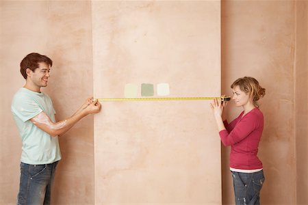 simsearch:695-03389240,k - Couple holding measuring tape to wall in unrenovated room Stock Photo - Premium Royalty-Free, Code: 693-03300526
