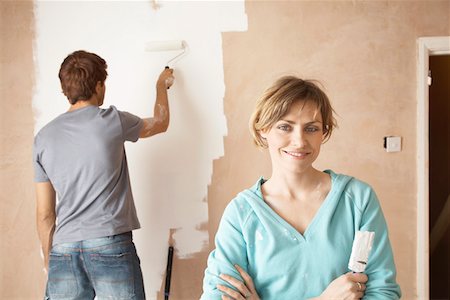 Woman holding paint brush next to man painting interior wall Stock Photo - Premium Royalty-Free, Code: 693-03300534