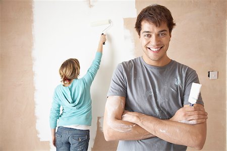 Couple painting interior wall using brush and roller Stock Photo - Premium Royalty-Free, Code: 693-03300535