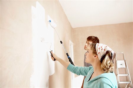 Couple painting wall with paint rollers indoors Stock Photo - Premium Royalty-Free, Code: 693-03300531