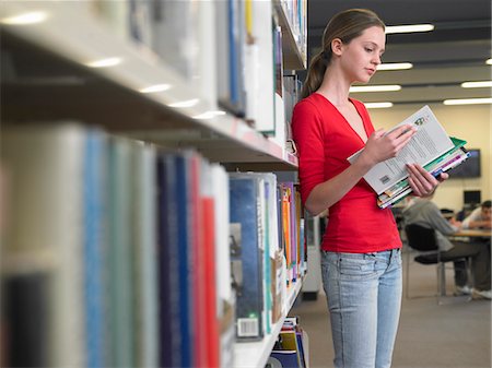 Teenage student reading text books by library shelf Stock Photo - Premium Royalty-Free, Code: 693-03300798
