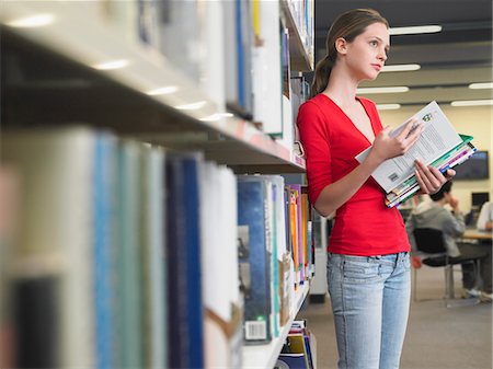 Teenage student reading text books by library shelf Stock Photo - Premium Royalty-Free, Code: 693-03300799