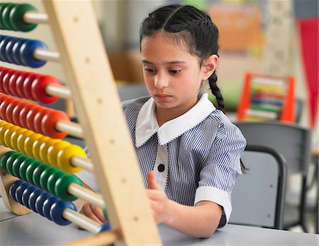 Schoolgirl using abacus in classroom Foto de stock - Royalty Free Premium, Número: 693-03300802