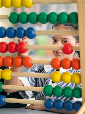 Elementary schoolgirl looking through abacus, sitting in classroom Foto de stock - Royalty Free Premium, Número: 693-03300803