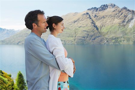 Couple embracing looking at mountain lake Stock Photo - Premium Royalty-Free, Code: 693-03300903