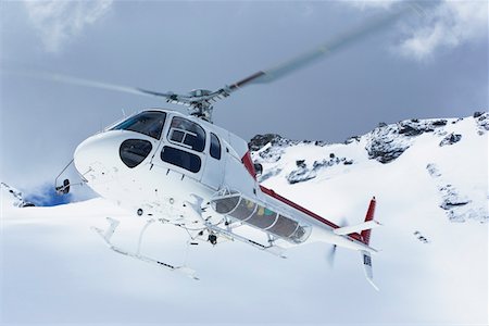 Helicopter flying over snowy mountain peaks Stock Photo - Premium Royalty-Free, Code: 693-03300922