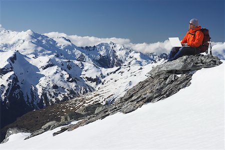 Alpiniste sur le sommet de la montagne à l'aide d'ordinateur portable Photographie de stock - Premium Libres de Droits, Code: 693-03300988