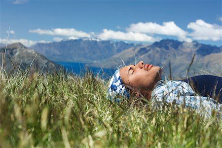 Man lying in field by lake and hills Fotografie stock - Premium Royalty-Free, Codice: 693-03301047