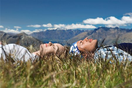 Man and woman lying in field overlooking hills Fotografie stock - Premium Royalty-Free, Codice: 693-03301049