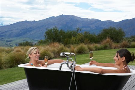 Two women taking bath with champagne on porch near mountains Stock Photo - Premium Royalty-Free, Code: 693-03301084